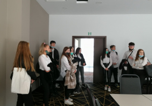 Grupa uczniów stoi w sali konferencyjnej